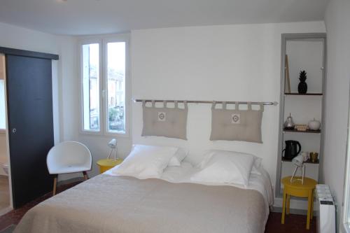 a bedroom with a white bed and a chair at La maison de jules in Moustiers-Sainte-Marie