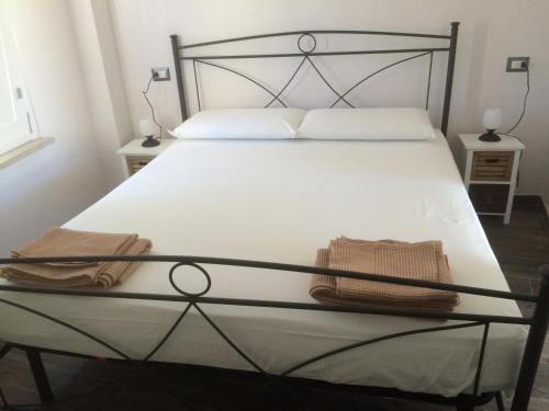 Una cama con un marco negro y dos toallas encima. en Il gabbiano, attico con terrazzo vista mare, en Peschici
