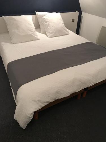 a large bed with white sheets and pillows at Le Tronçais in Saint-Bonnet-Tronçais