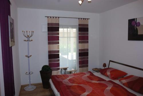 a bedroom with a bed with a red comforter at Reiger Ferienwohnungen in Wackersdorf