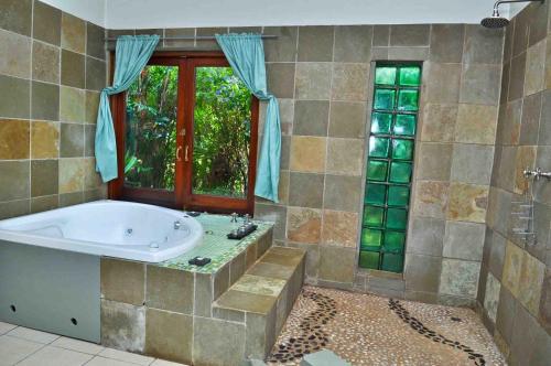 a large bathroom with a tub and a window at Bali at Willinga lodge Located in Kosmos in Hartbeespoort