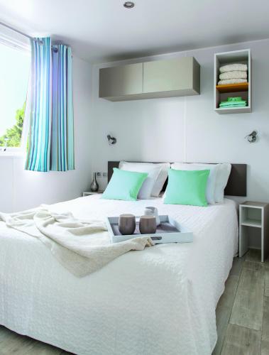 a bedroom with a white bed with a tray on it at Camping Resort Les Champs Blancs in Agde