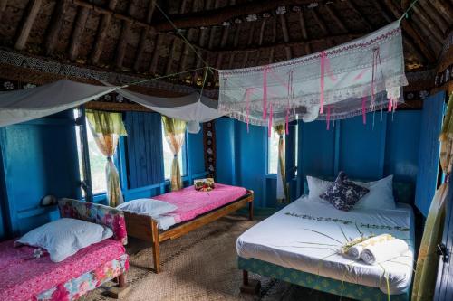 2 camas en una habitación con paredes azules en Yasawa Homestays, en Nacula Island