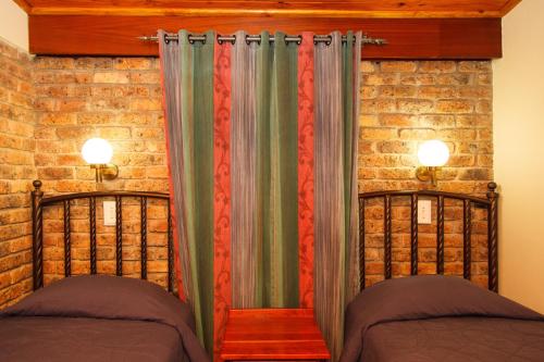 a bedroom with two beds and a brick wall at Swadini, A Forever Resort in Hoedspruit