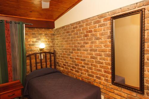a bedroom with a brick wall and a mirror at Swadini, A Forever Resort in Hoedspruit