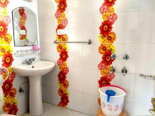 La salle de bains est pourvue d'un lavabo et de fleurs sur le mur. dans l'établissement Hotel Victoriya palace, à McLeod Ganj