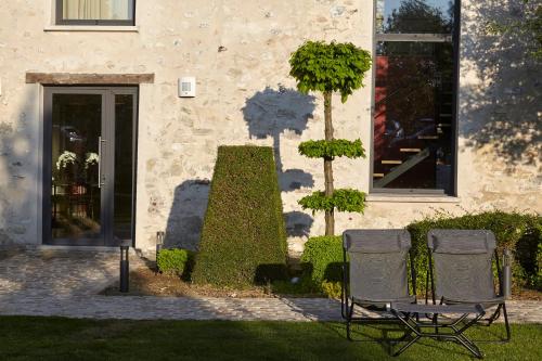 two chairs sitting in front of a building at Chambre d'hôtes Les Herbes Folles in Mauregard