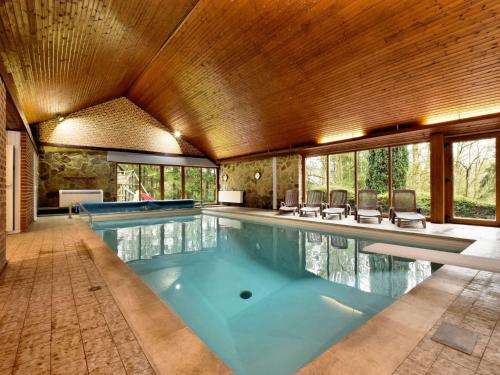 a large swimming pool with chairs in a house at Luxurious Villa with Private Pool in Durbuy in Grandhan