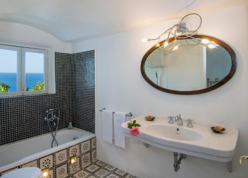 a bathroom with a sink and a tub and a mirror at Villa Lindo in Maiori