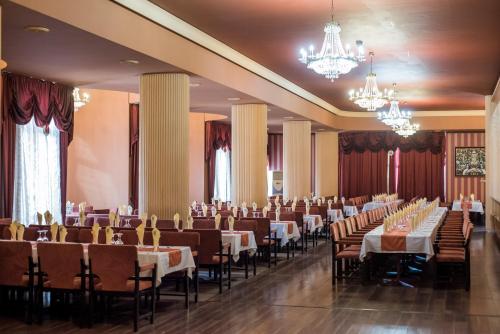 einen Bankettsaal mit Tischen, Stühlen und Kronleuchtern in der Unterkunft Hotel Balkan in Plewen