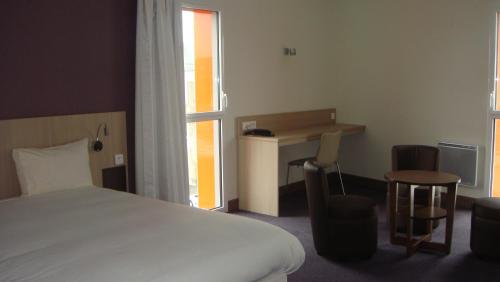 um quarto com uma cama, uma secretária e uma janela em The Originals Access, Hôtel Cholet Gare em Cholet