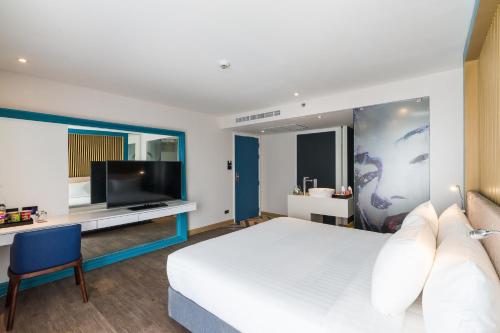 a hotel room with a bed and a tv at Citrus Grande Hotel Pattaya by Compass Hospitality in Pattaya South
