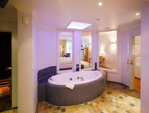 Romantik Hotel Hof zur Linde في مونستر: حمام مع حوض استحمام مع مرآة كبيرة
