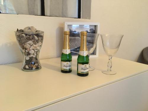 three bottles of wine and a glass on a dresser at Landhaus zum adeligen Klosterforst in Pohnsdorf