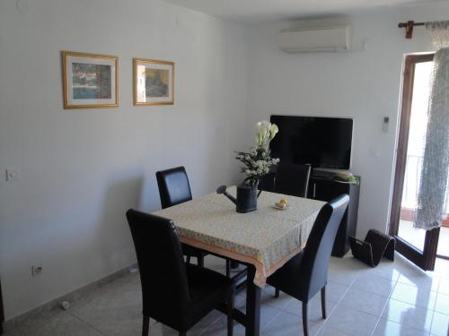 ein Esszimmer mit einem Tisch, Stühlen und einem TV in der Unterkunft Apartments Niki - 5m from the sea in Drvenik Veli