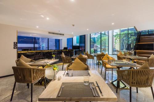 a restaurant with tables and chairs and windows at Citrus Grande Hotel Pattaya by Compass Hospitality in Pattaya South