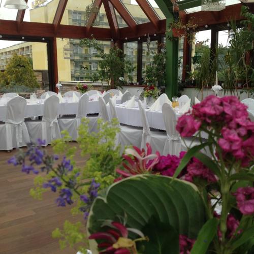 a group of tables with white chairs and flowers at SeaPark Hotel Wellness & Spa in Kołobrzeg