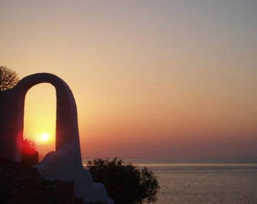 a sunset over the ocean with a statue in the foreground at ILIDI Rock in Livadia