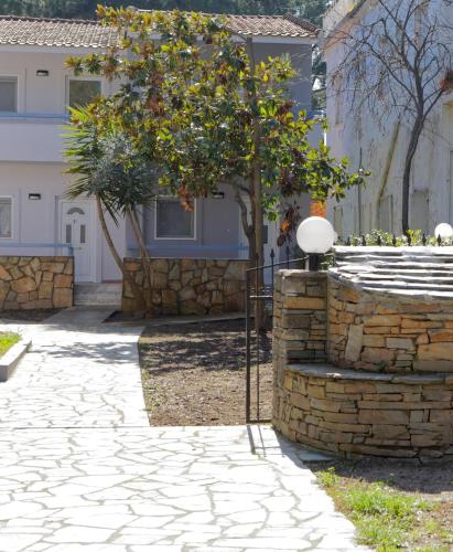 a stone walkway with a tree in front of a house at BLEU- VERT in Prinos