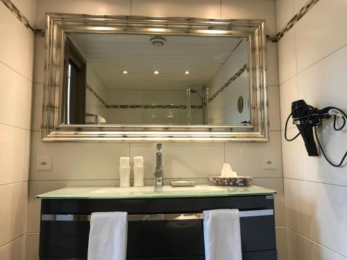 ein Bad mit einem Waschbecken und einem Spiegel in der Unterkunft Bodenseehotel Weisses Rössli in Staad