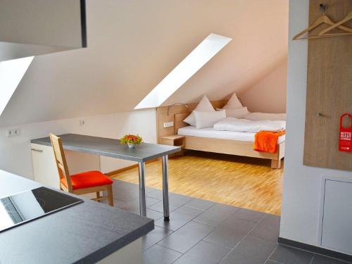 a kitchen with a table and a room with a bed at Apparthotel Ampertal in Kranzberg