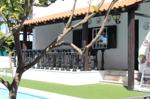 a house with a balcony with a tree in the foreground at Hostel Casa Lucas in Charneca