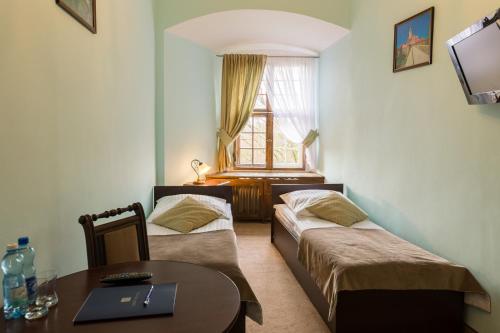 a room with two beds and a table and a window at Zamek Czocha in Leśna