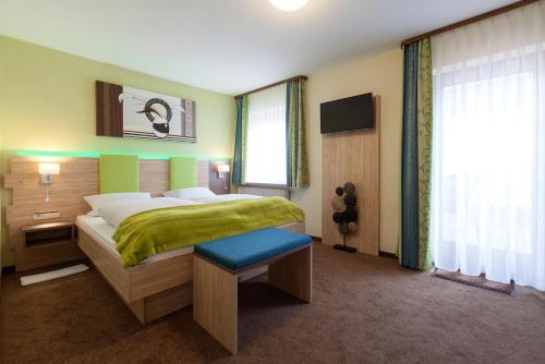 a bedroom with a large bed with a green blanket at Landhotel Traube in Seewald