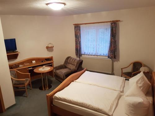 a bedroom with a bed and a desk and a chair at Land-gut-Hotel Zur Lochmühle in Penig