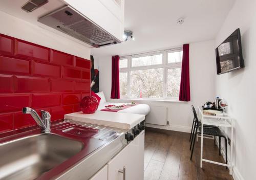 a kitchen with red walls and a sink at Wembley Park Hotel in London
