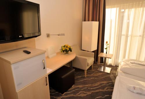 a hotel room with a bed, tv and a desk at Heikotel - Hotel Am Stadtpark in Hamburg