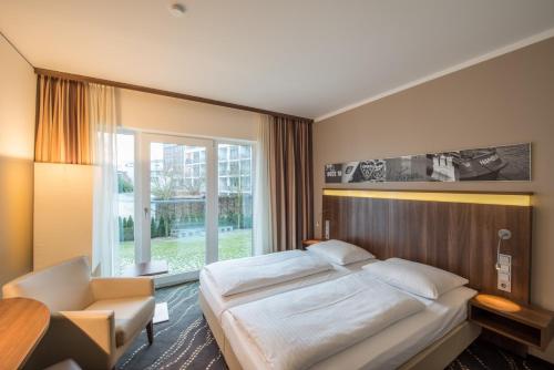 um quarto com uma cama, uma cadeira e uma janela em Heikotel - Hotel Am Stadtpark em Hamburgo