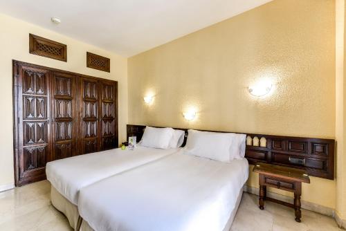 una camera da letto con un grande letto bianco e una finestra di Hotel Sercotel Alfonso VI a Toledo