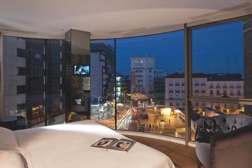 een slaapkamer met een groot raam met uitzicht op de stad bij Hotel Santo Domingo in Madrid