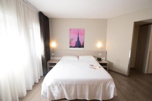 a bedroom with a white bed and a picture of a tower at Best Quality Hotel Politecnico in Turin