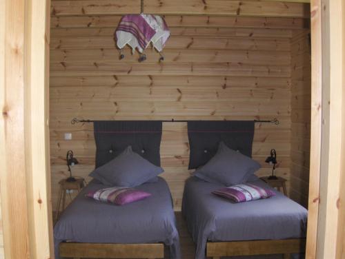 2 Betten in einem Zimmer mit einer Holzwand in der Unterkunft Les Bruchels, Longechaux in Longechaux