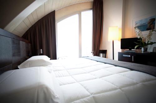 a large white bed in a room with a window at Hotel Mosaico & Residence in Ravenna