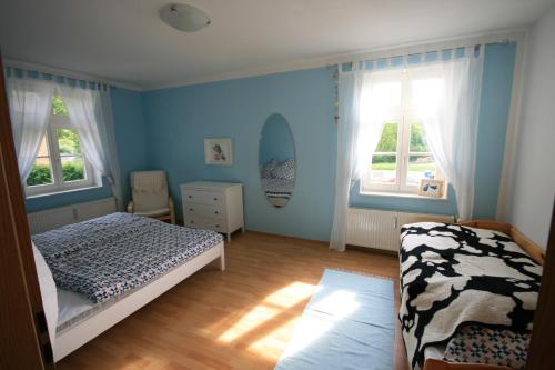 a bedroom with blue walls and a bed and two windows at Ferienhaus Schwalbe Seebad Lubmin in Lubmin