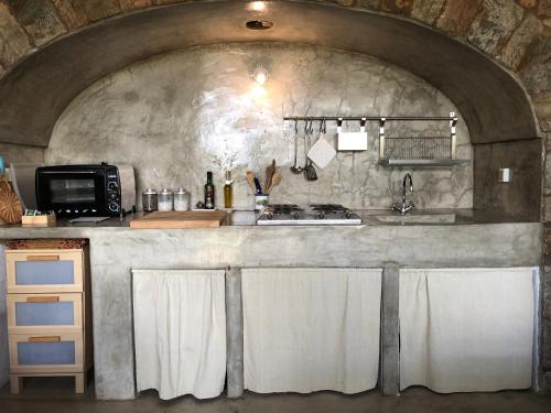 a kitchen with a stone wall with a sink and a microwave at Etherea - I Dammusini di Pantelleria in Pantelleria