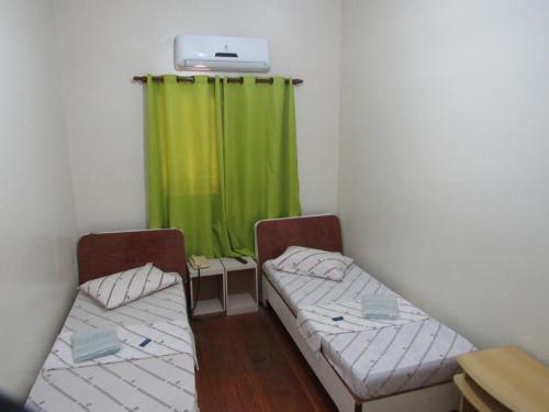 two beds in a room with a green curtain at Hotel Moraes a 10 minutos da 25 de Março,Brás,Bom Retiro,a 2 minutos do Mirante Sampa Sky e pista de Skate Anhangabaú in Sao Paulo
