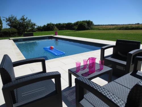 - une piscine avec 2 chaises et une table avec des verres dans l'établissement Le Grand Coudreau, à Nazelles-Négron