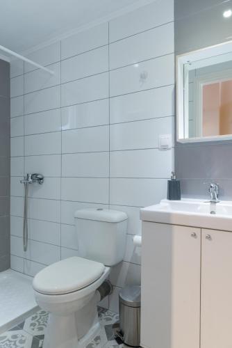 a white bathroom with a toilet and a sink at Tamaris Beach House in Acharavi