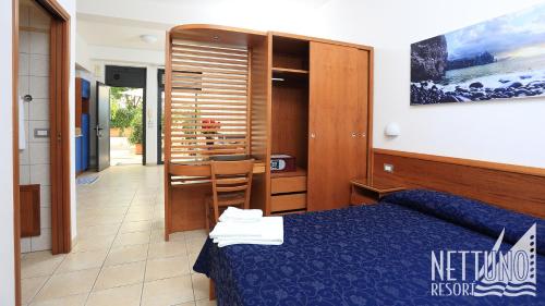 a bedroom with a blue bed and a dining room at Nettuno Resort in Capo dʼOrlando