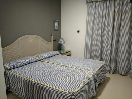 a bedroom with a bed and a window with curtains at Hotel Pineda Playa in Noja