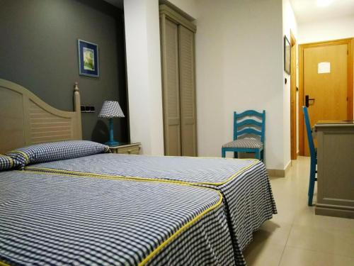 a bedroom with a bed and two blue chairs at Hotel Pineda Playa in Noja