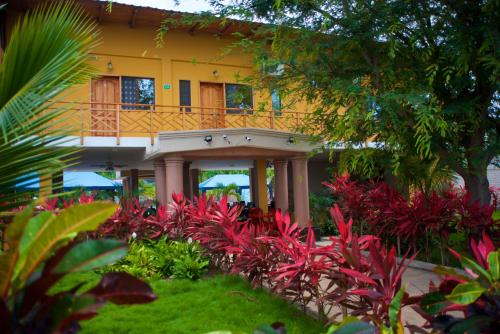 a yellow house with a balcony in a garden at Hotel Soberao in Esmeraldas