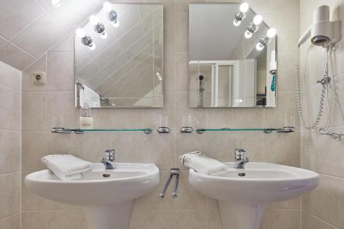 a bathroom with two sinks and a mirror at Hotel garni Sonnenhof in Reichenberg