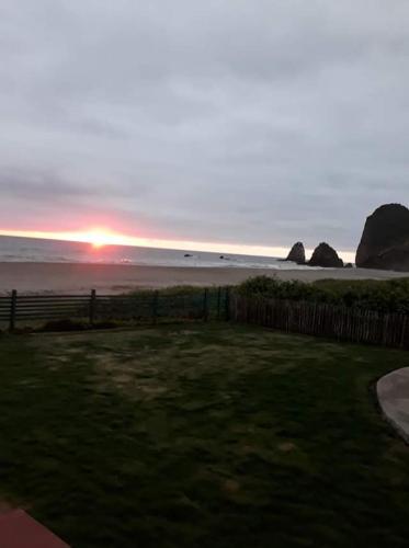 a sunset over the ocean with rocks and a fence at The Lookout Beach Hotel in San Lorenzo