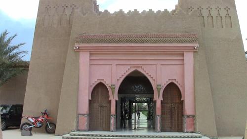 a pink building with a motorcycle parked in front of it at Belere Arfoud in Erfoud