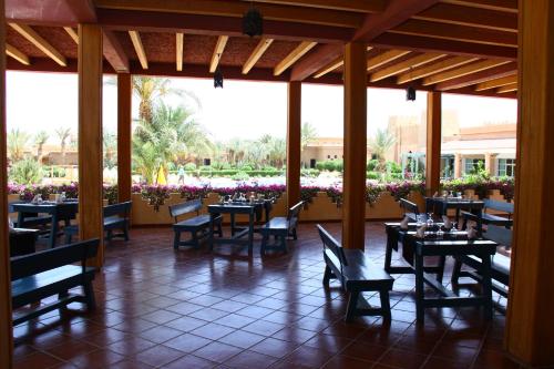 a dining room with tables and chairs and flowers at Belere Arfoud in Erfoud